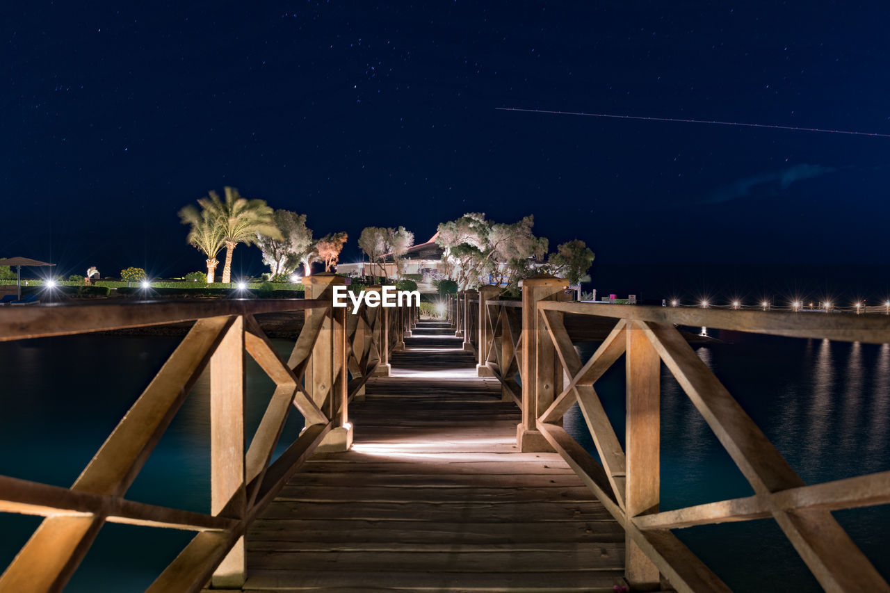 Staircase by sea against sky at night