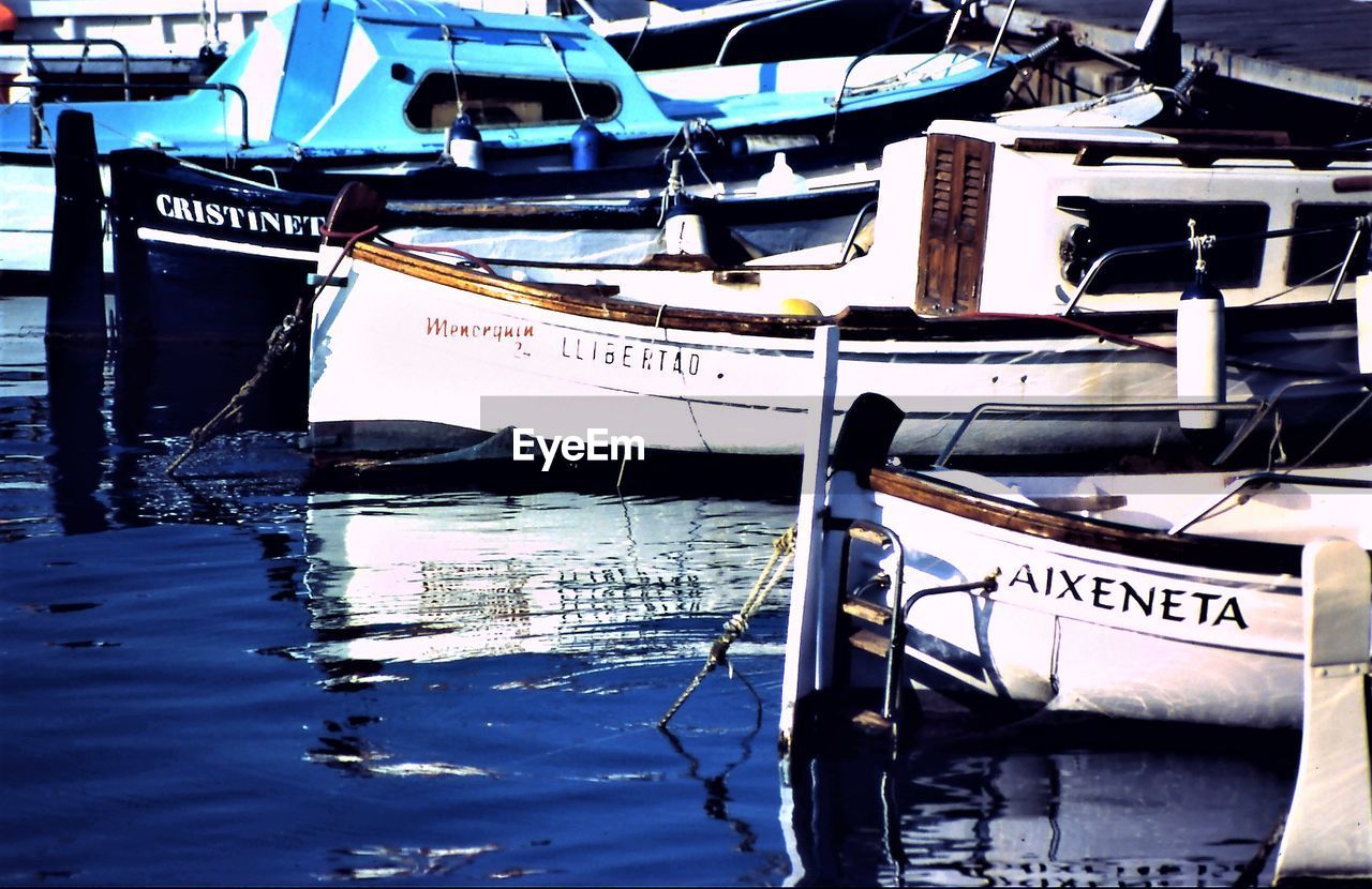 BOATS MOORED AT HARBOR BY RIVER