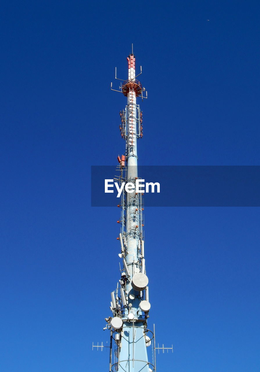 Low angle view of communications tower against blue sky