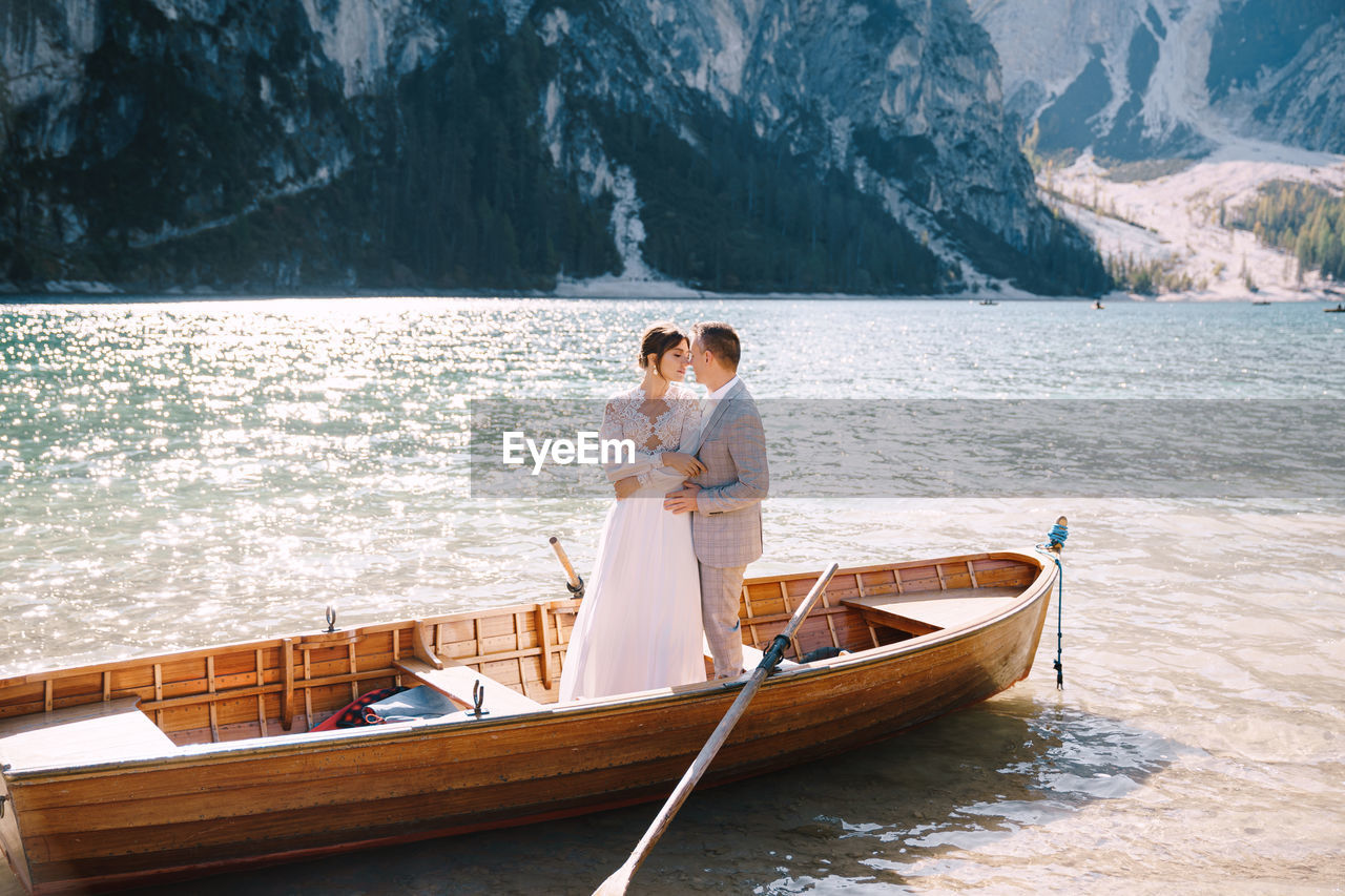 COUPLE STANDING ON BOAT IN LAKE