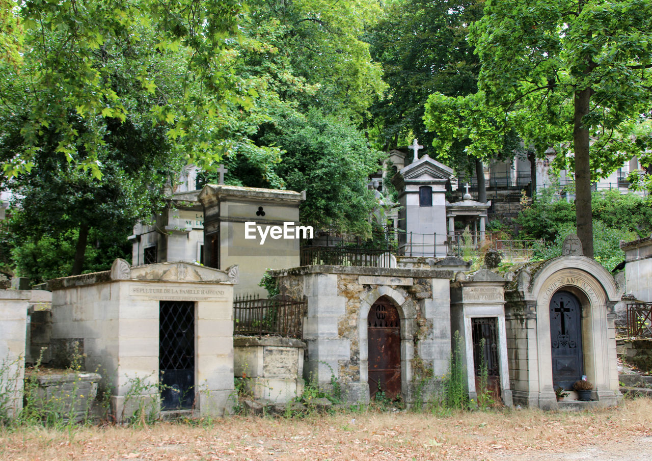 Exterior of old graves by trees on graveyard