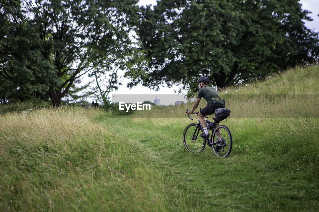 Full length of man riding bicycle on grassy land