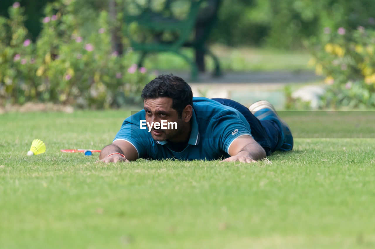 grass, men, one person, lawn, sports, plant, lying down, adult, green, leisure activity, relaxation, lifestyles, nature, casual clothing, selective focus, surface level, young adult, outdoors, day, person, player, athlete, activity, portrait, front view, copy space, lying on front, exercising, emotion, weekend activities, concentration