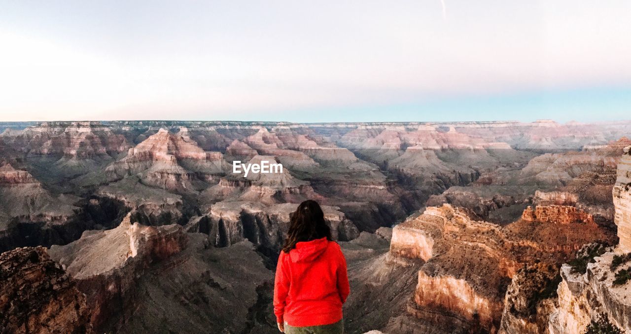 REAR VIEW OF WOMAN WALKING ON ROCKS