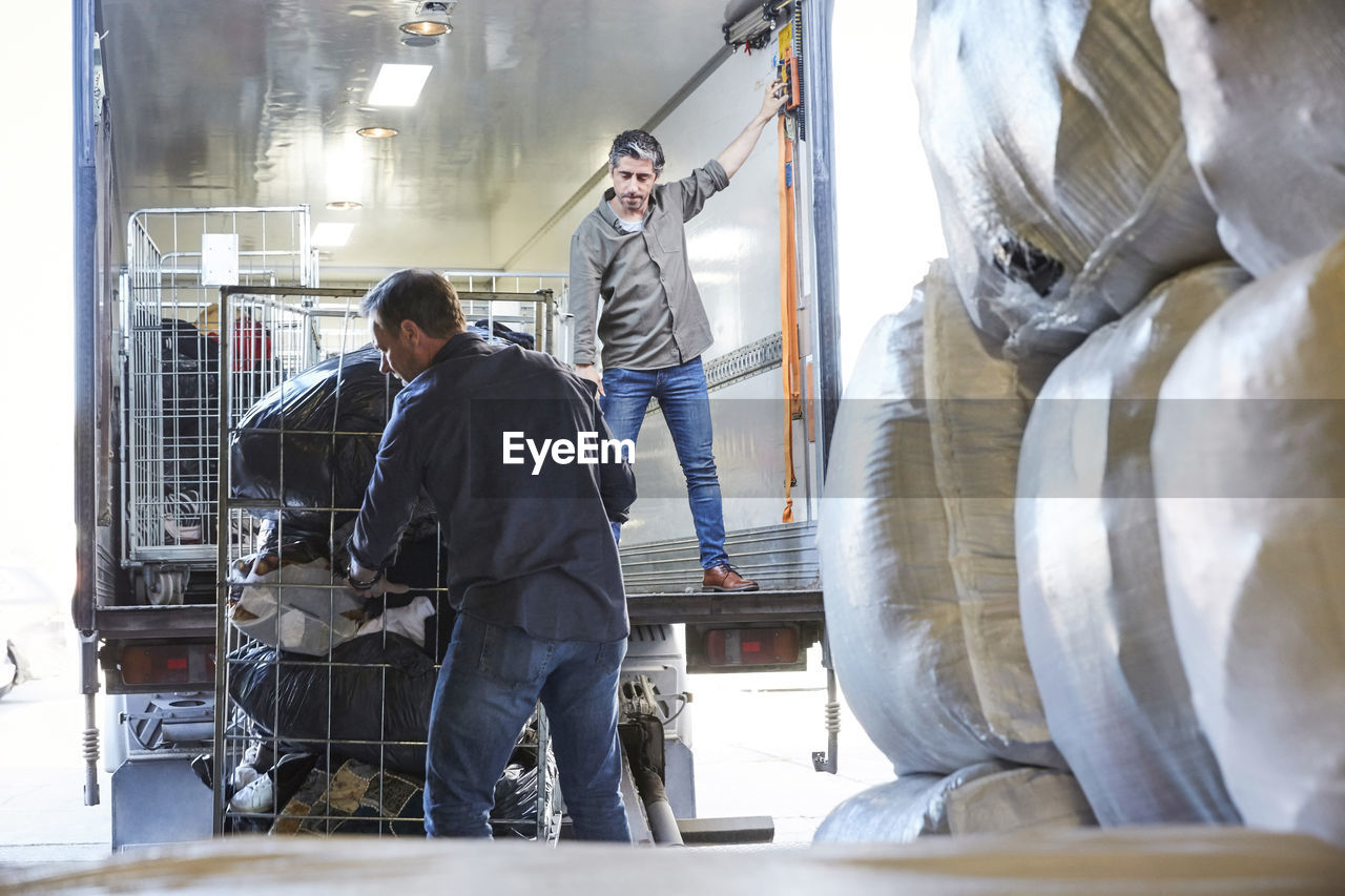 Mature coworkers unloading semi-truck at warehouse