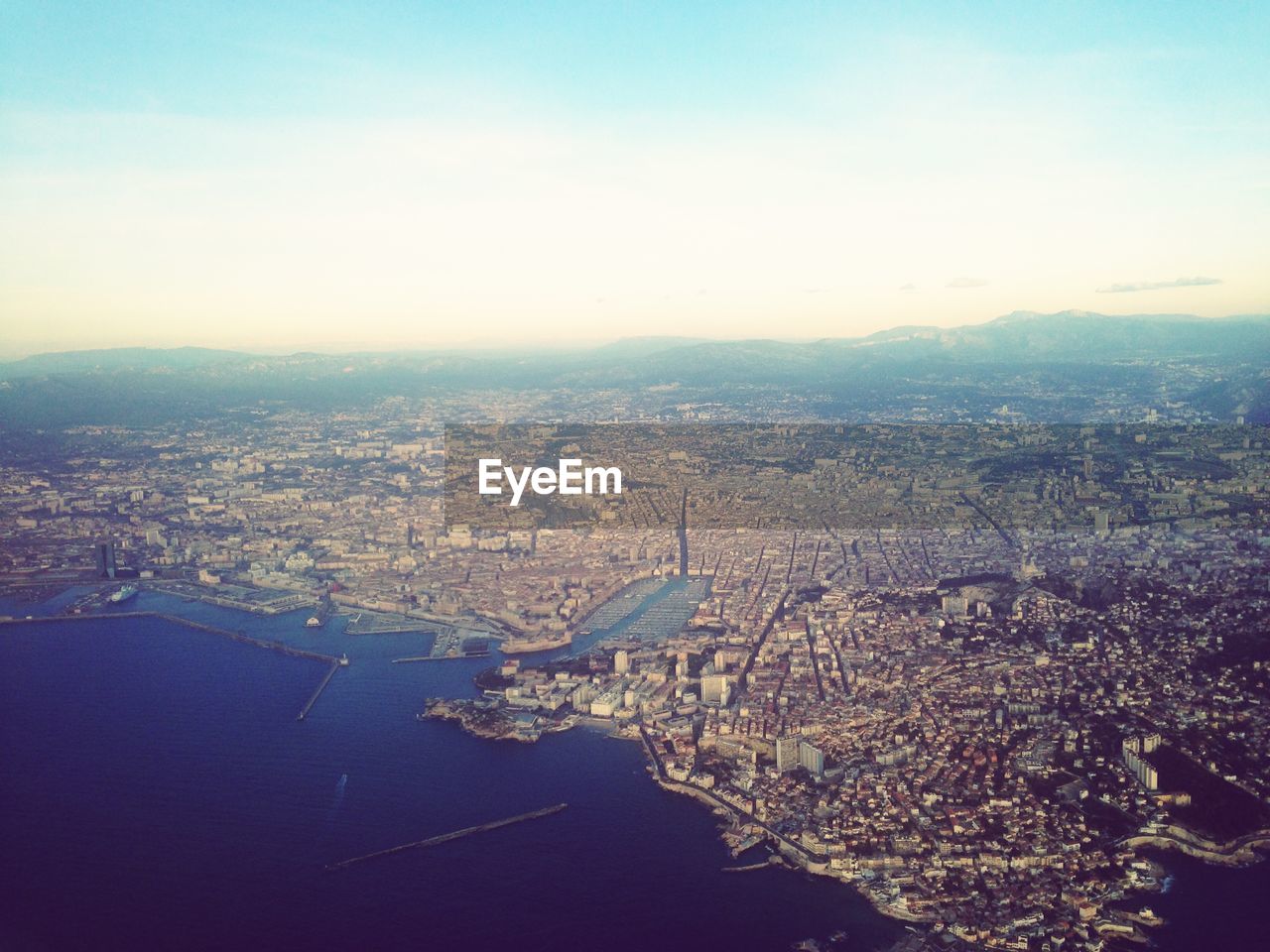 Aerial view of sea and cityscape against sky