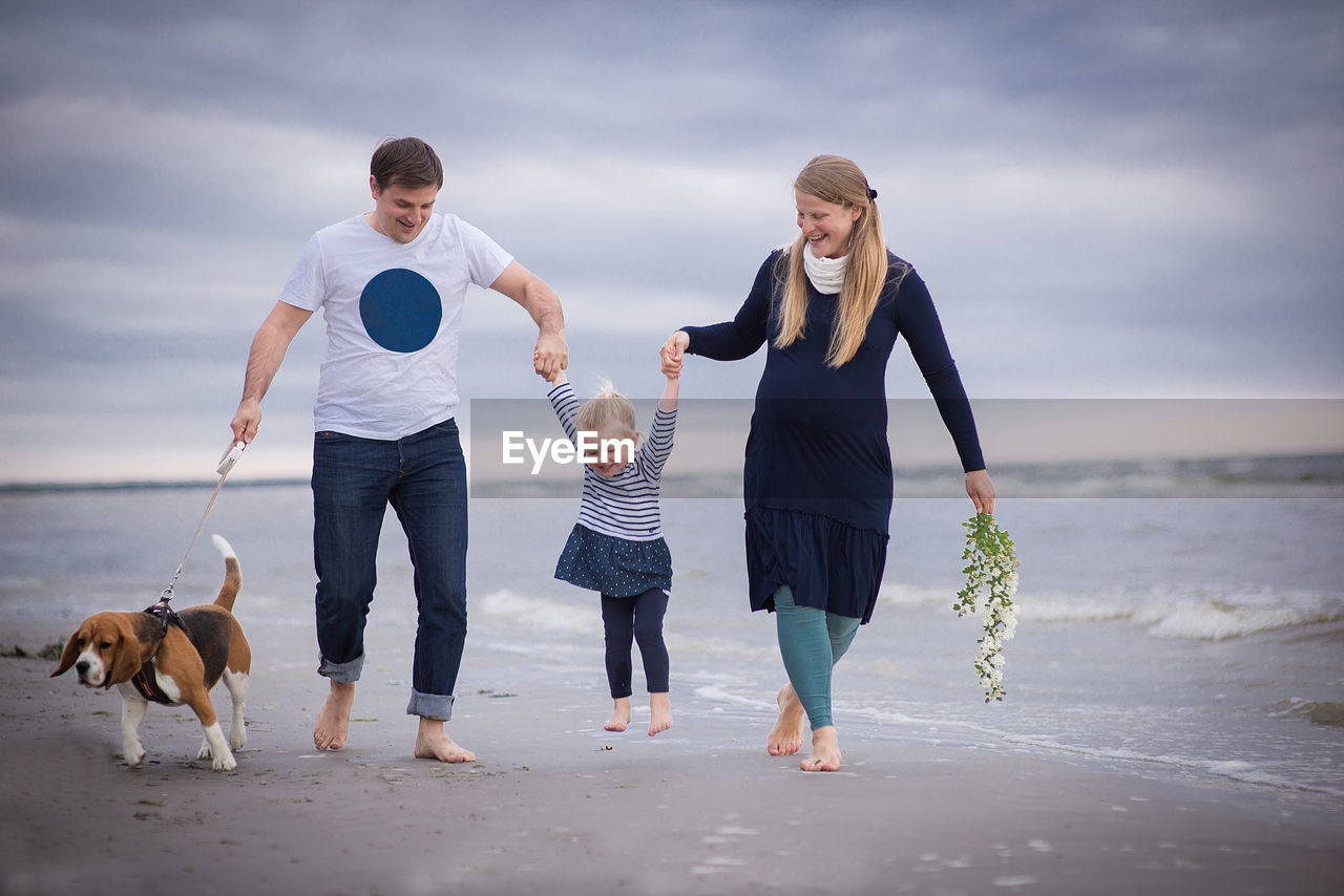 Full length of happy family walking at beach