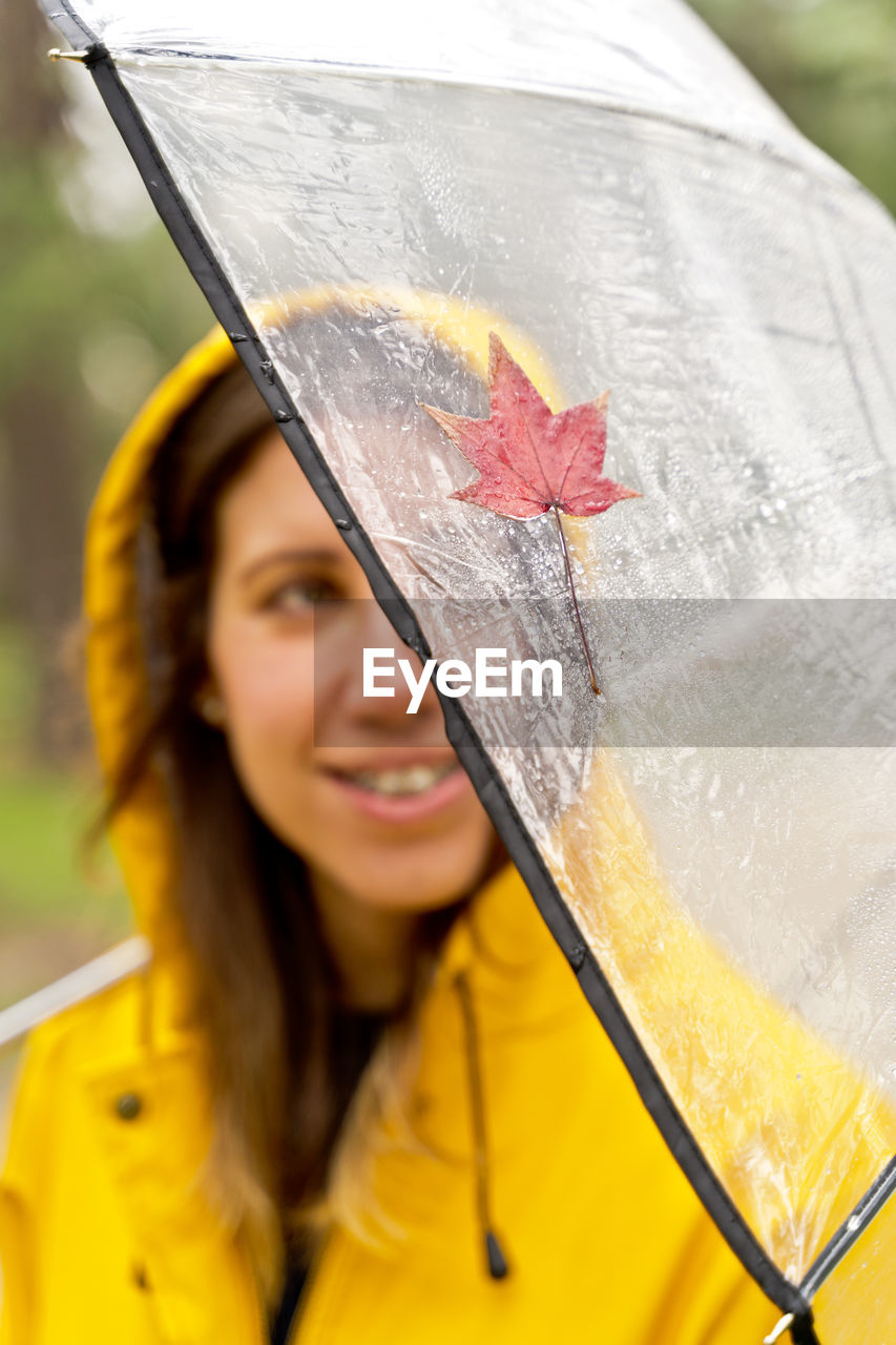 Smiling girl holding umbrella during rain