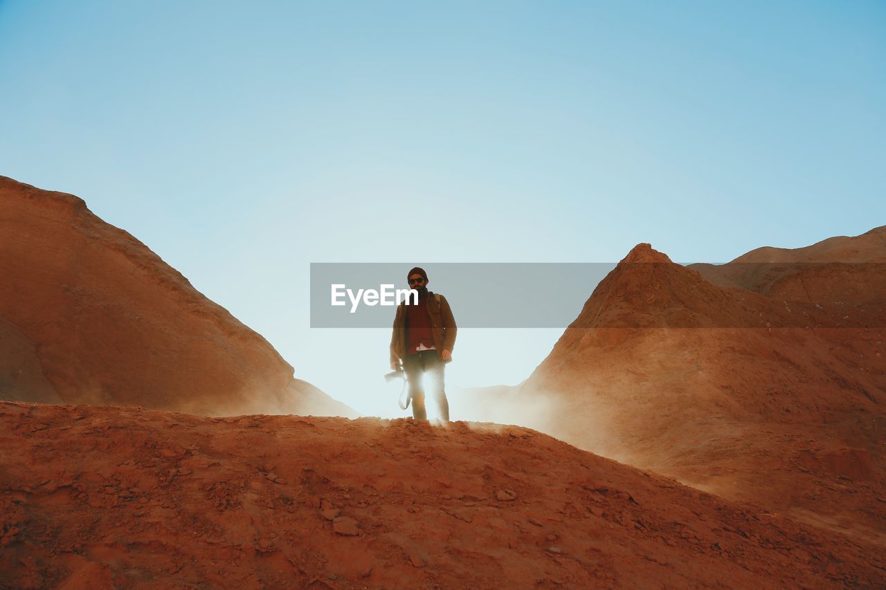 Low angle view of man standing on mountain against clear sky