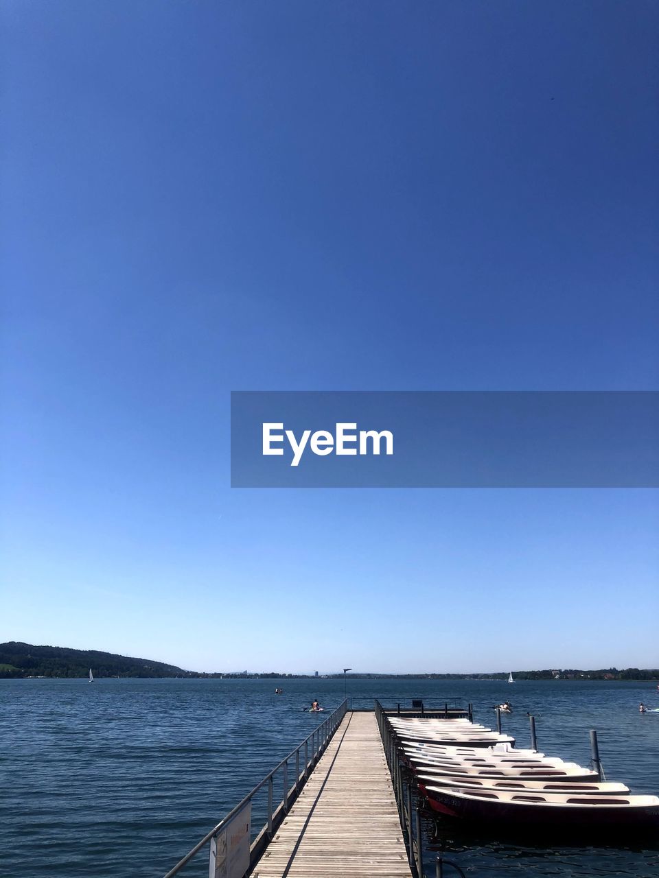 Pier over sea against clear blue sky