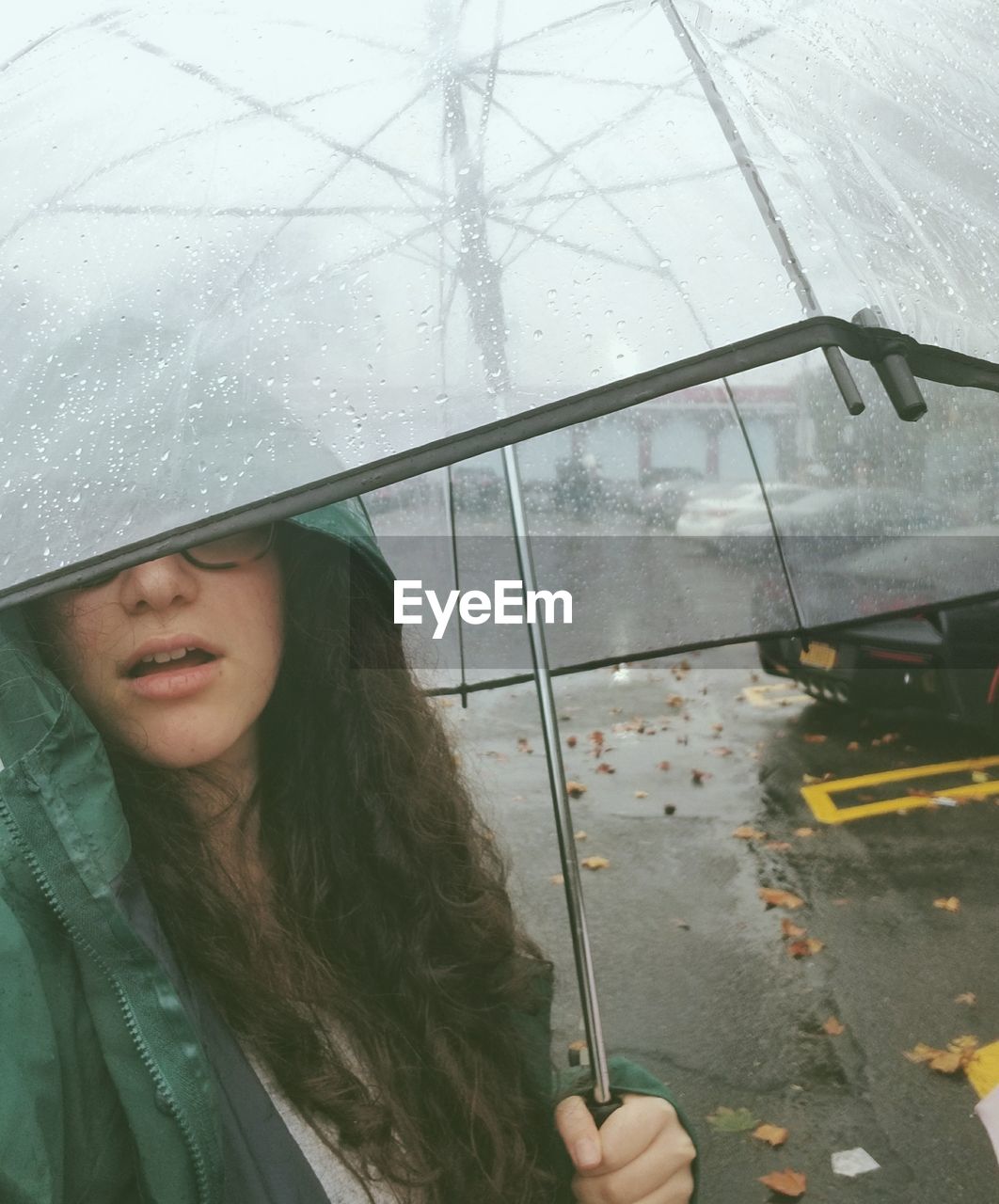 Close-up of young woman holding umbrella during rainy season