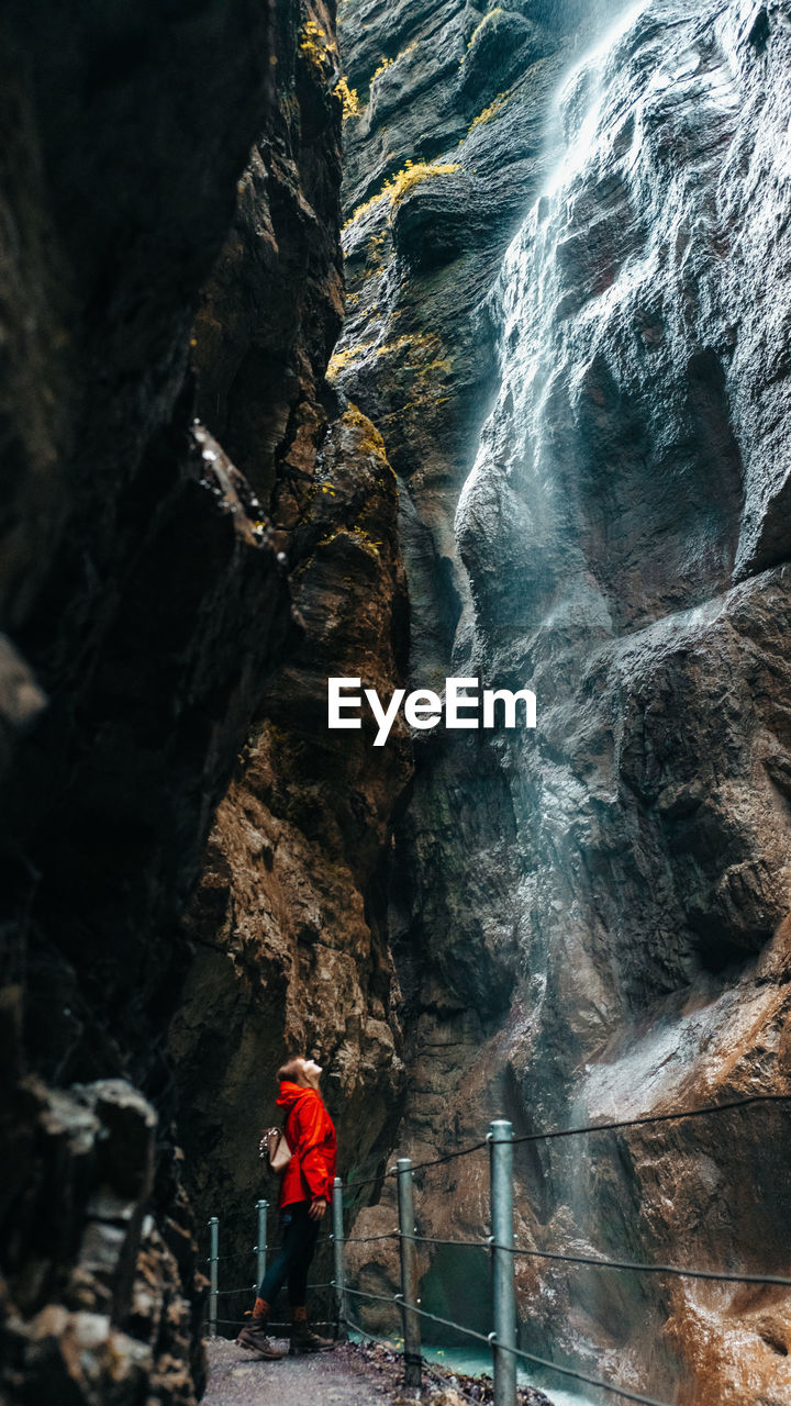 Full length of woman standing by waterfall