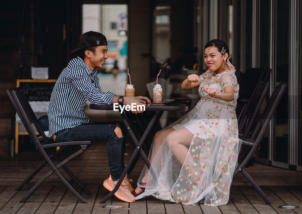 Full length of couple sitting at cafe