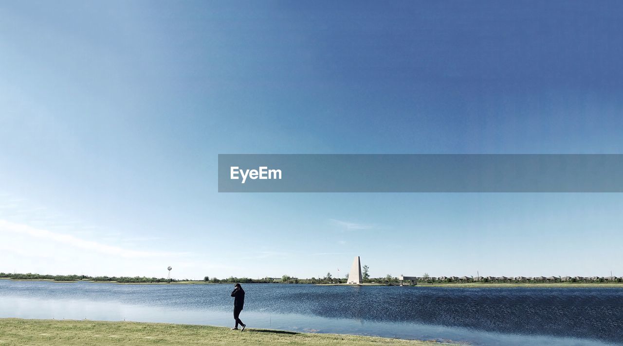 Side view of a silhouette man walking by the lake