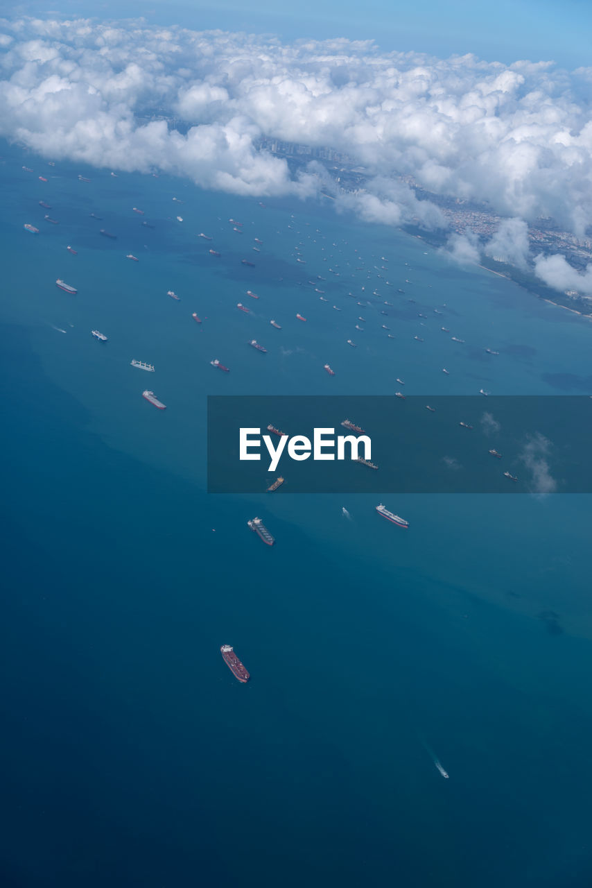 Aerial view above the clouds, below is the bay, with many cargo boats singapore. soft focus.
