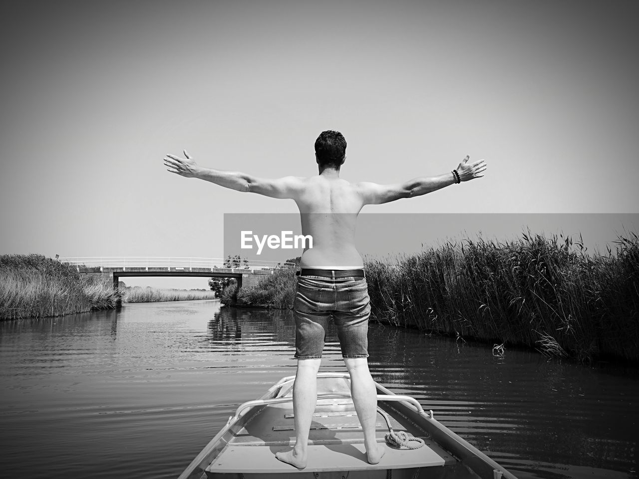 REAR VIEW OF SHIRTLESS MAN STANDING IN LAKE