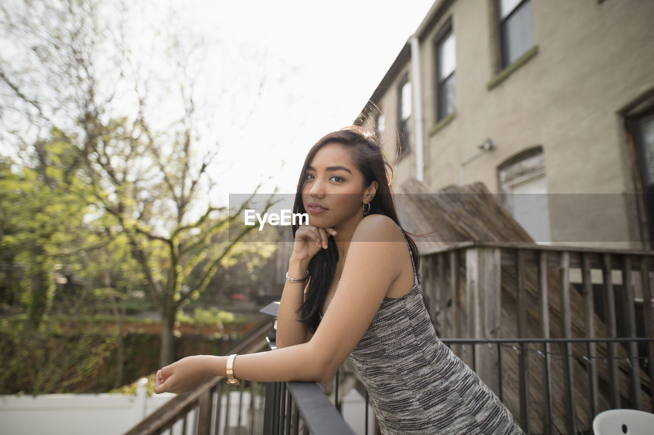 Young woman leaning on her balcony railing