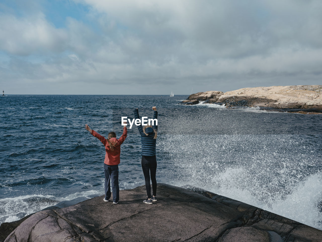 Rear view of mother and daughter standing at sea