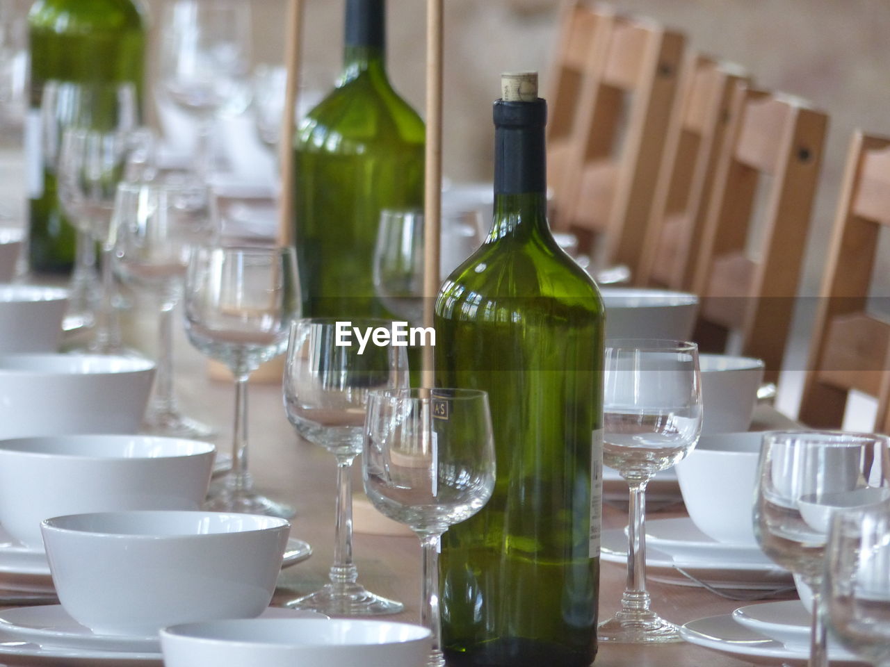 Wineglasses with bowls arranged by wine bottles on table