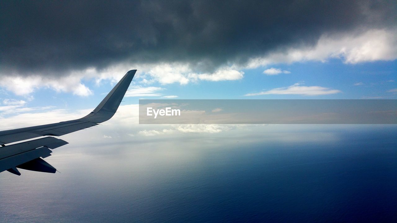 Cropped image of airplane over sea against sky