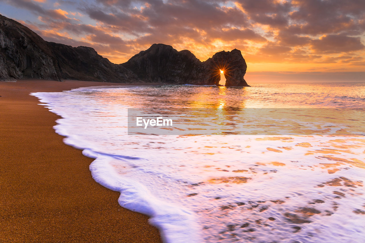 Scenic view of sea against dramatic sky during sunset