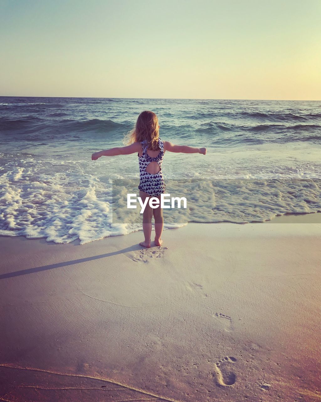 REAR VIEW OF YOUNG WOMAN AT BEACH