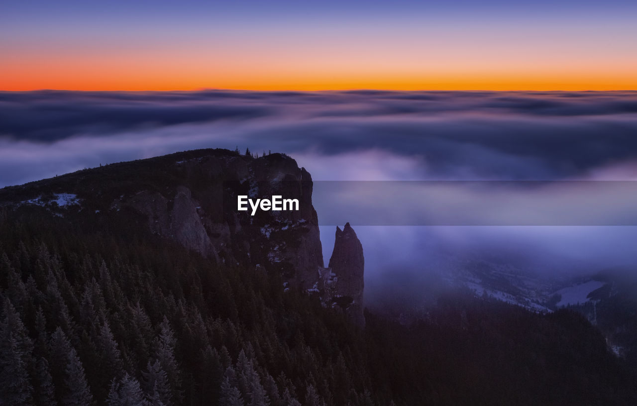 Scenic view of mountain against cloudy sky during sunset