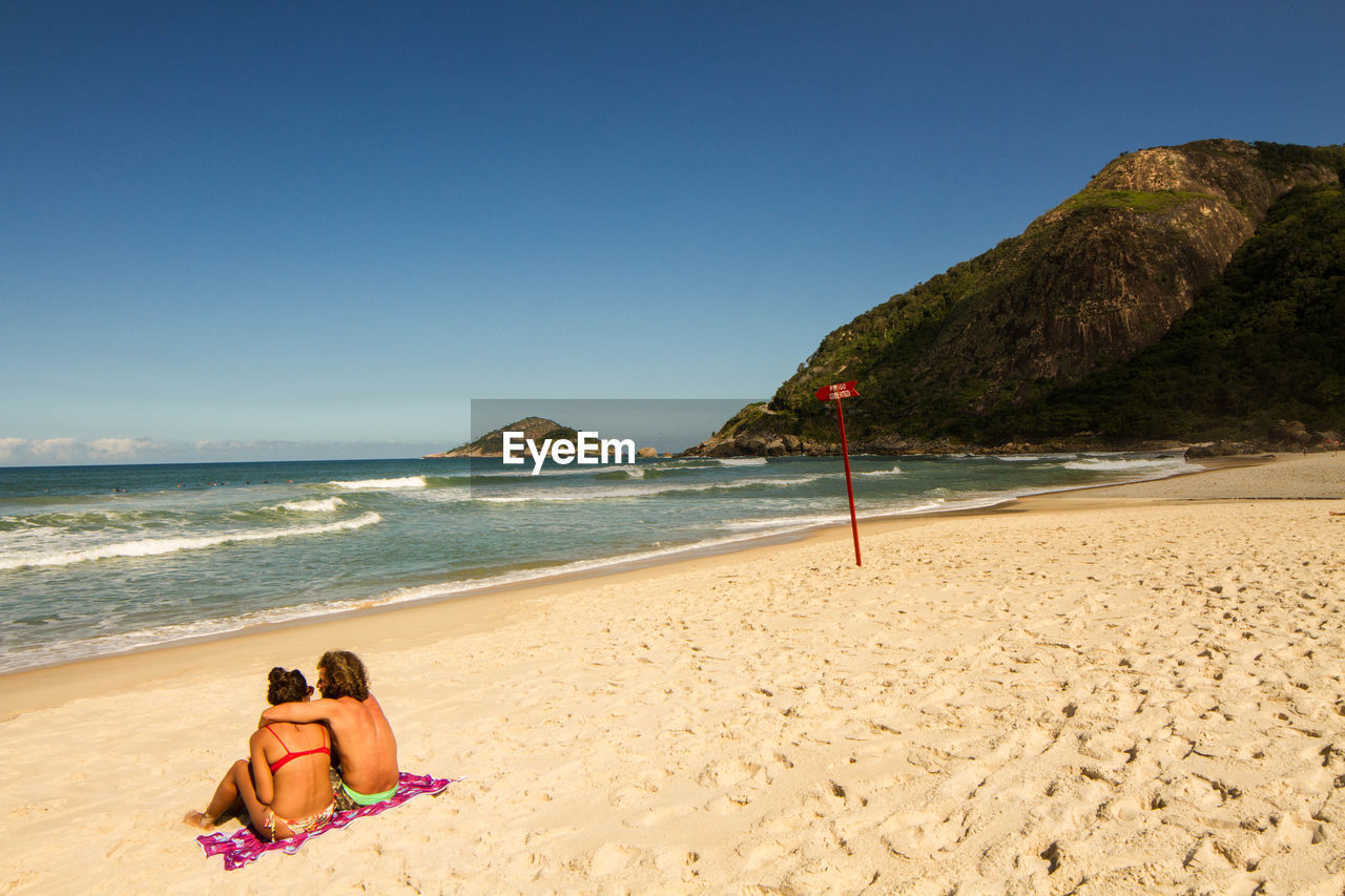 High angle view of couple sitting at shore of beach