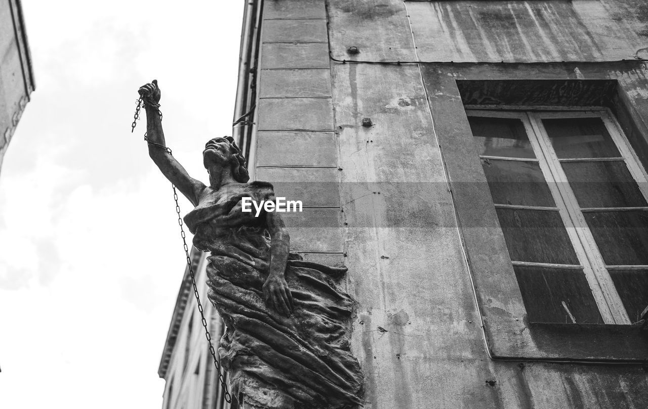 Low angle view of statue against building. she raises her fist to the sky like a sign of protest