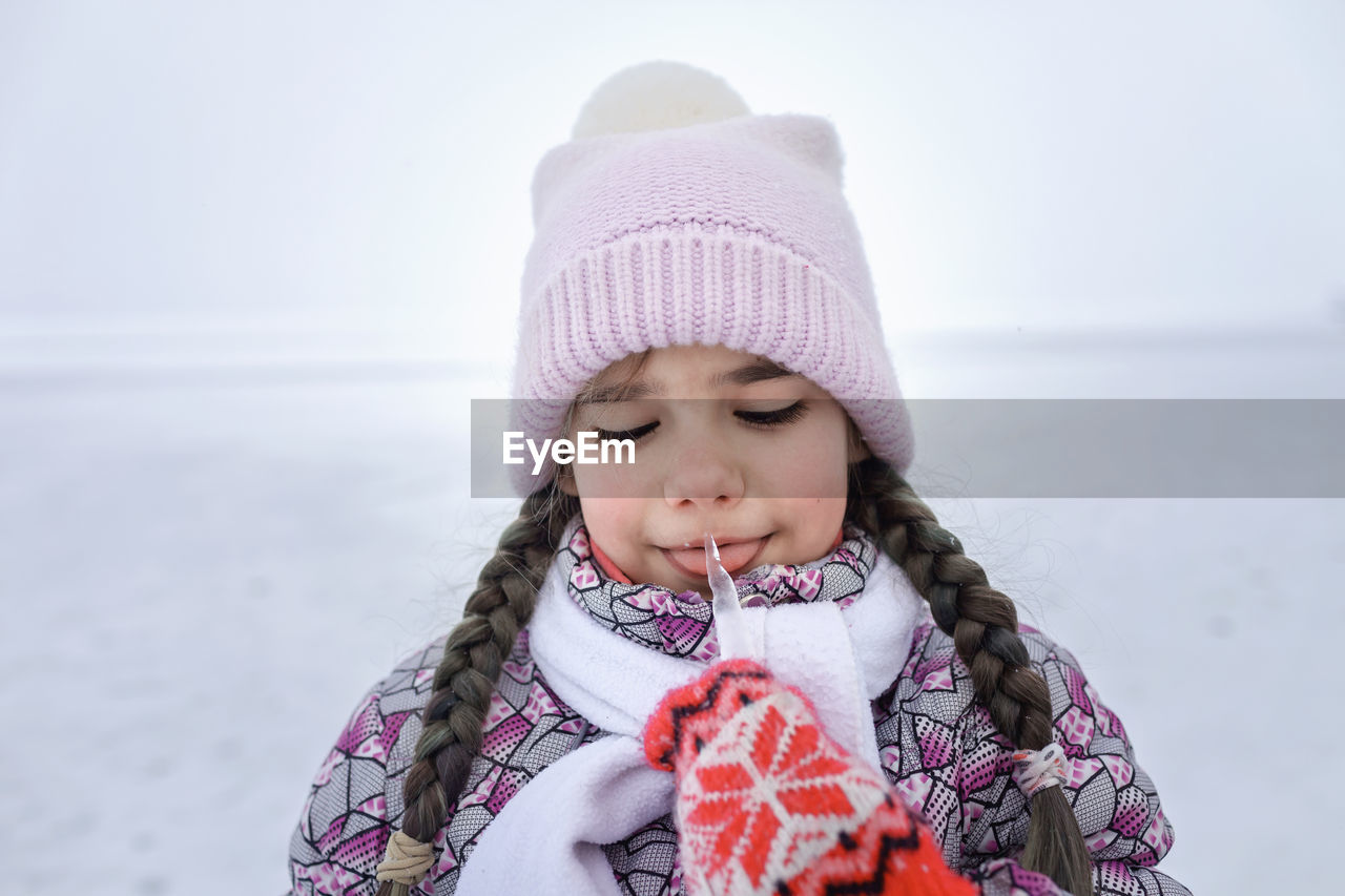 Cute girl licking ice during winter