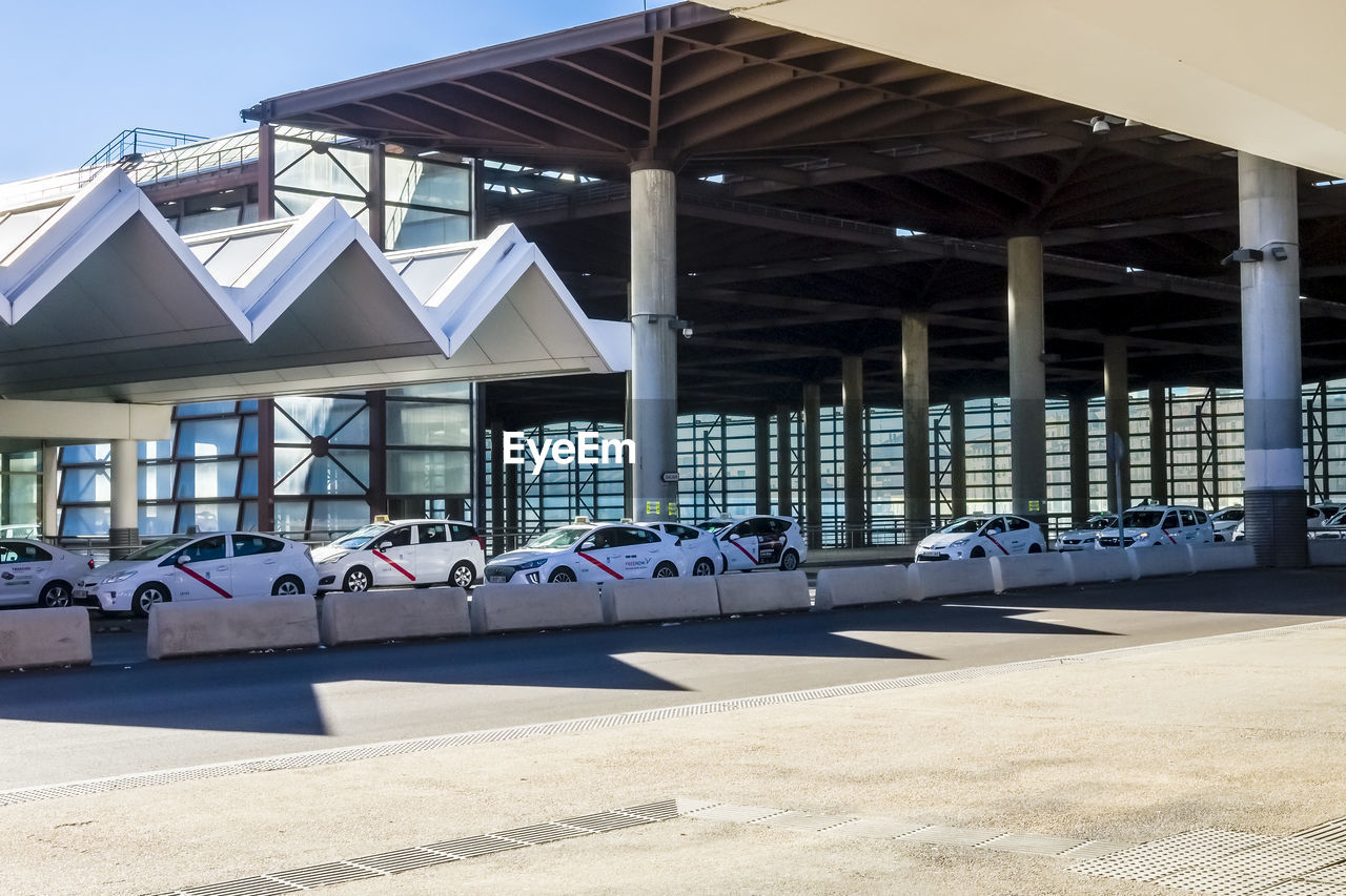 View of built structures with a line of taxi cabs at a taxi rank.