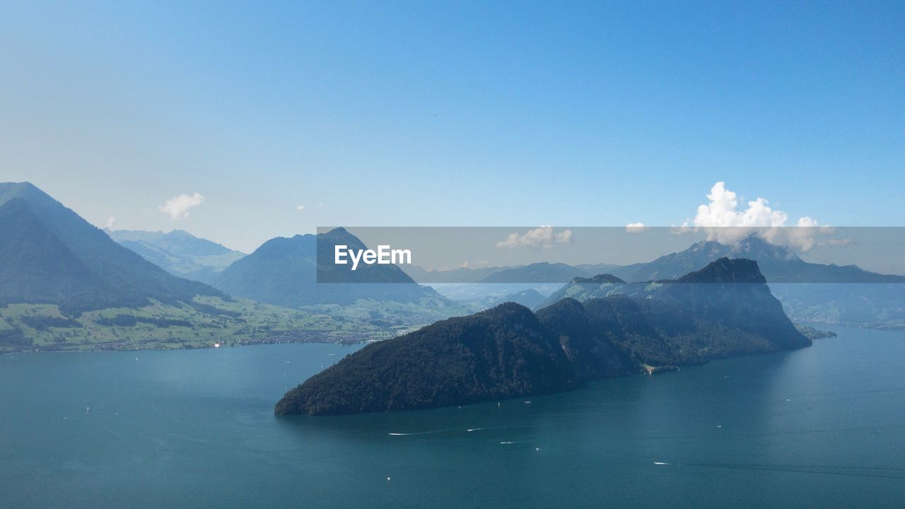 Scenic view of sea and mountains against blue sky