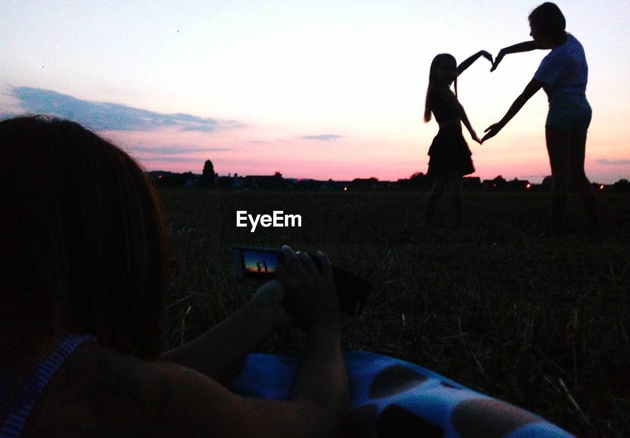 MEN PHOTOGRAPHING ON FIELD AGAINST SKY