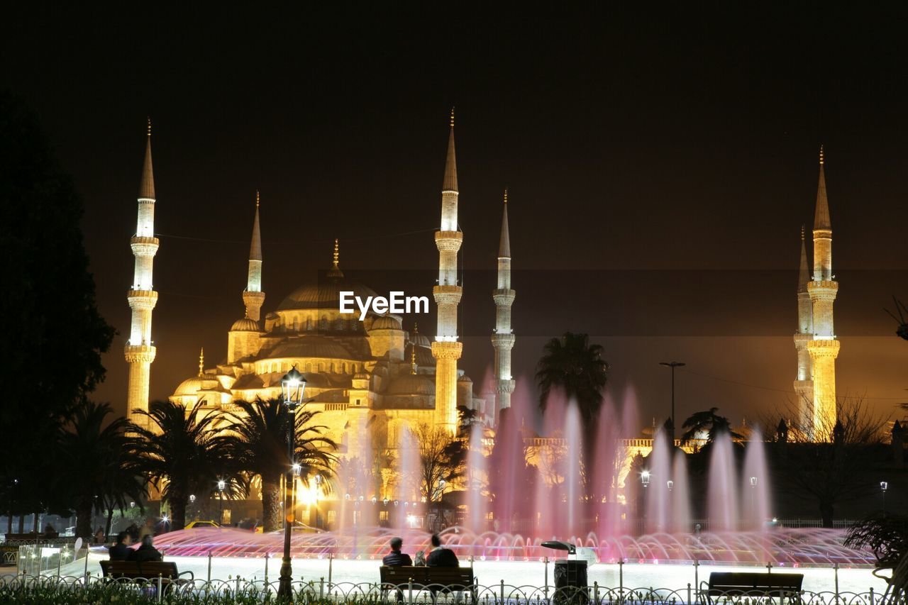 LOW ANGLE VIEW OF ILLUMINATED BUILDING AT NIGHT