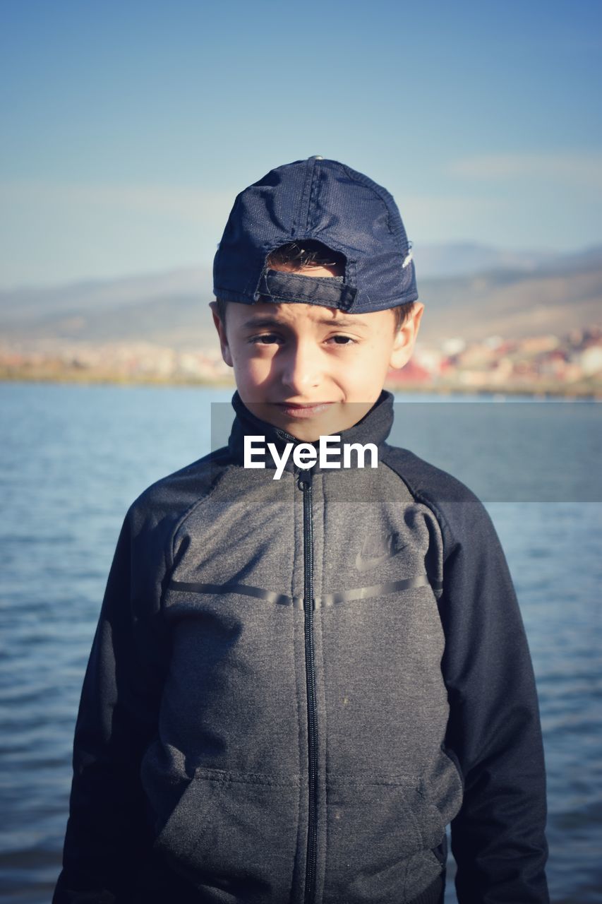 PORTRAIT OF BOY STANDING AGAINST SEA