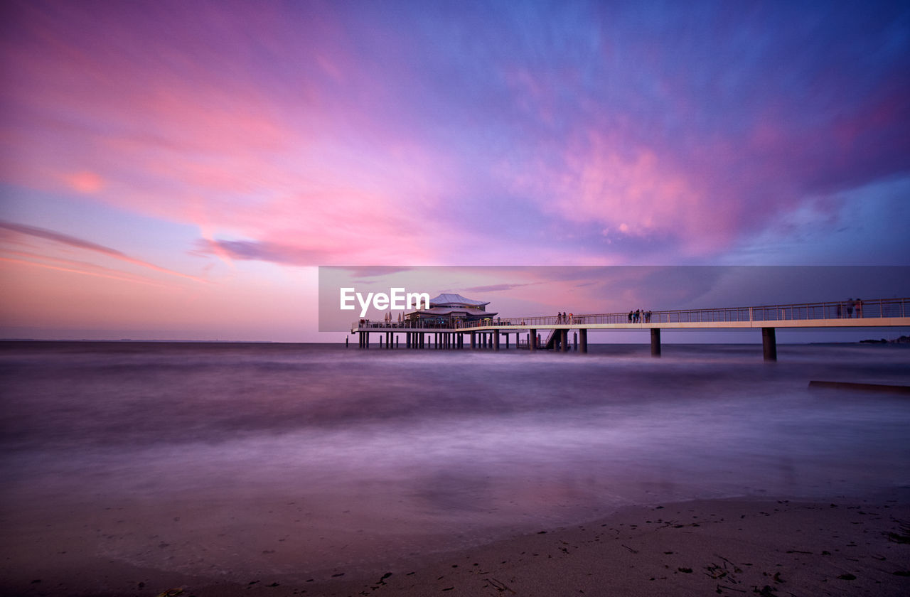 Pier over sea against sky at sunset