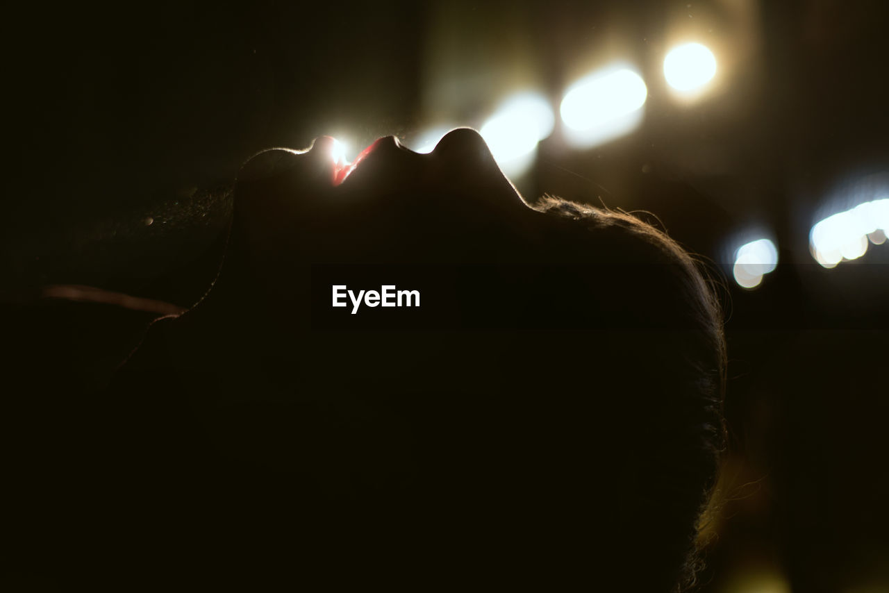 Close-up of man against illuminated lights at night