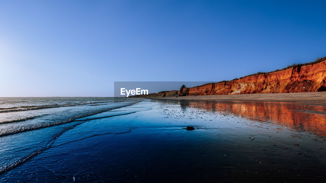 water, reflection, sky, sea, scenics - nature, nature, land, shore, body of water, beauty in nature, dusk, horizon, coast, blue, morning, ocean, clear sky, environment, landscape, travel destinations, tranquility, beach, travel, wave, tranquil scene, no people, sunrise, outdoors, rock, sunlight, non-urban scene, tourism, bay, copy space, day, idyllic, animal, sand, cloud, lagoon, sunny