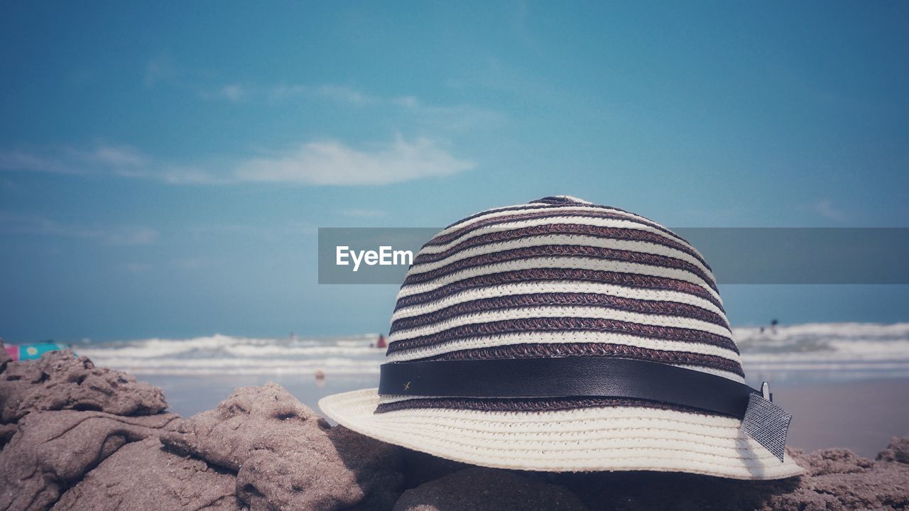 Close-up of hat on rock against sky