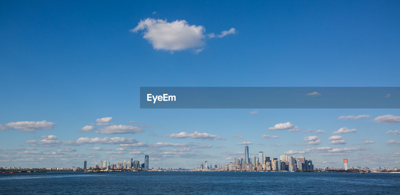 City at waterfront against cloudy sky