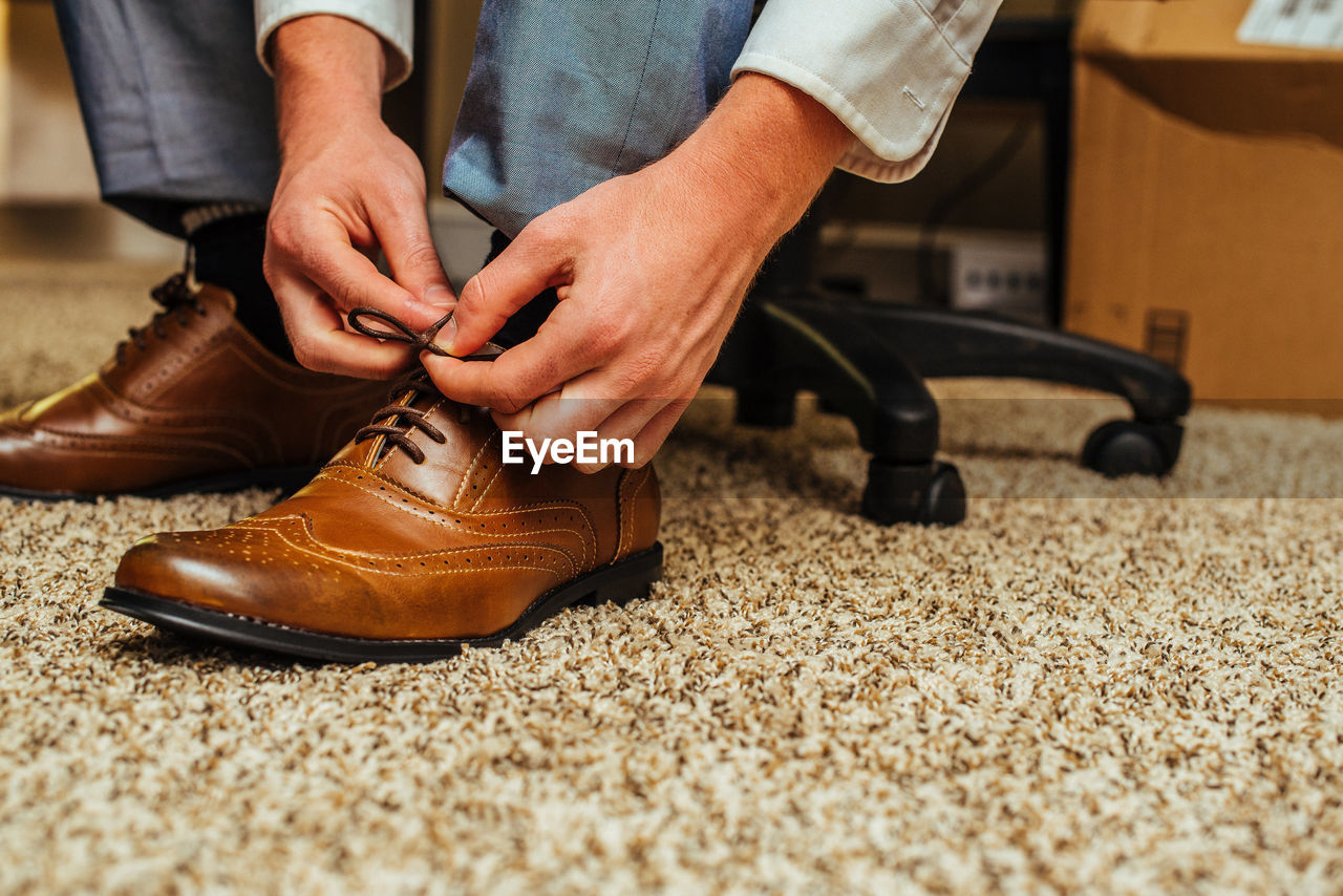 Low section of businessman tying shoes in office