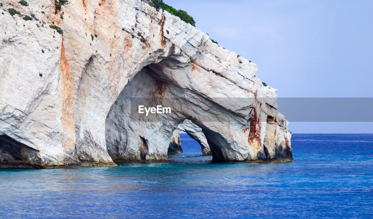 Rock formation in sea against sky