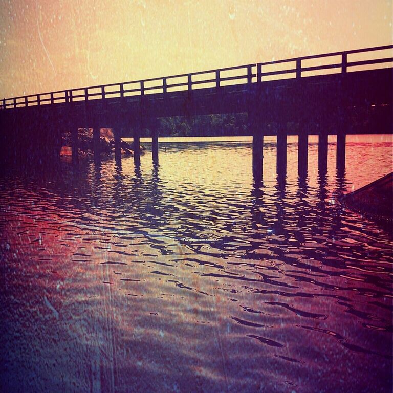 Bridge over river against sky at dusk