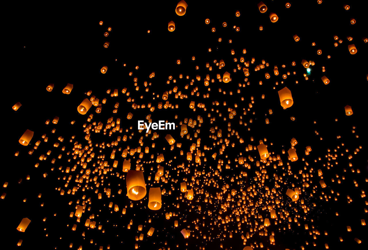 Low angle view of lanterns flying against sky at night