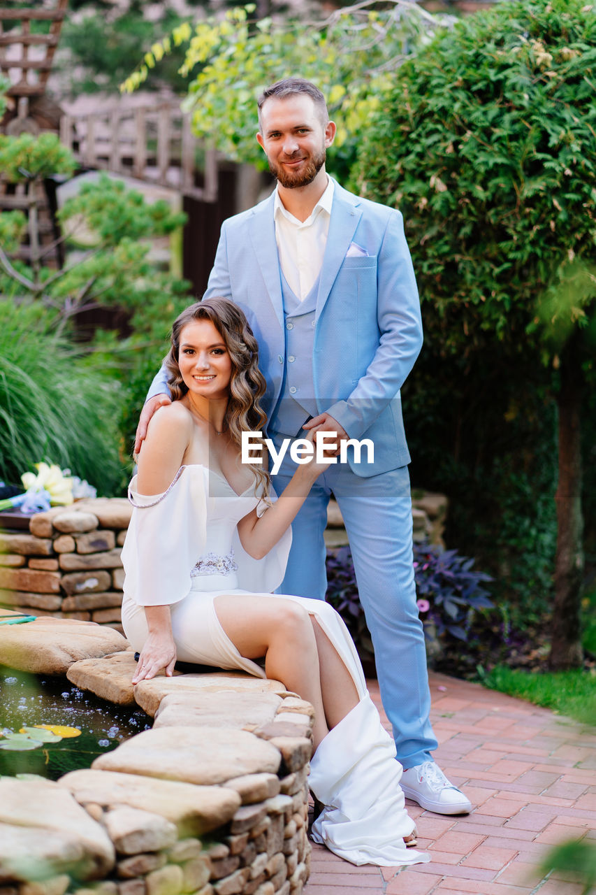 Newlywed couple embracing while standing outdoors