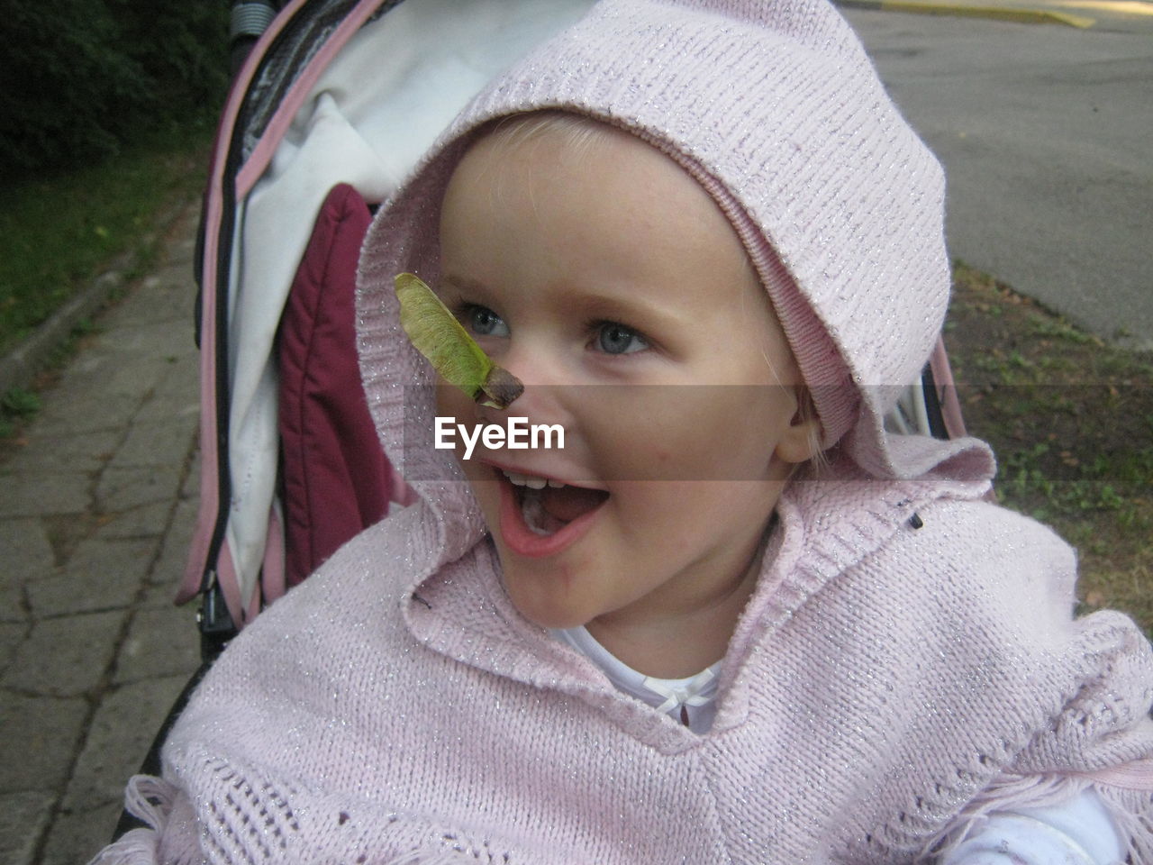 Close-up of thoughtful girl with leaf on nose in baby stroller