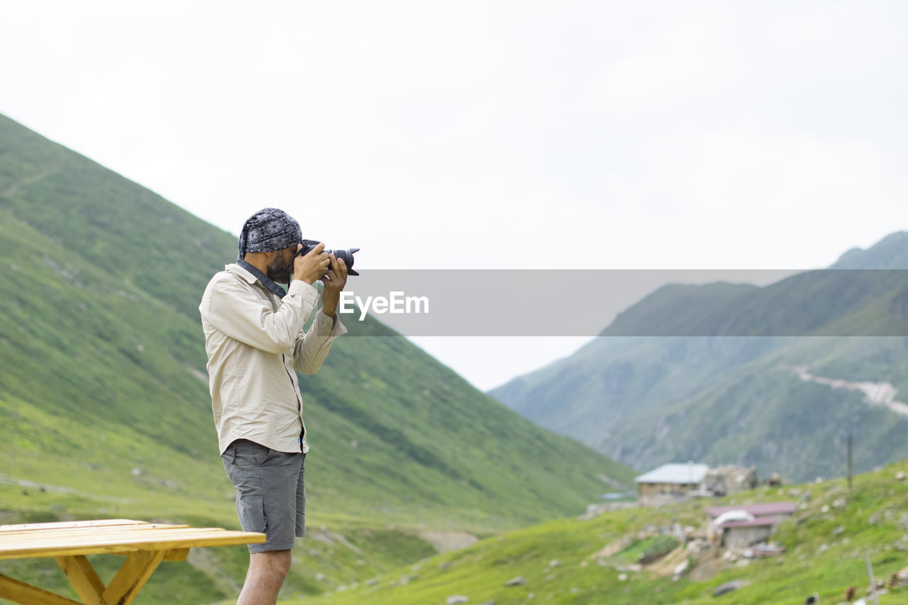 MAN PHOTOGRAPHING ON MOUNTAIN