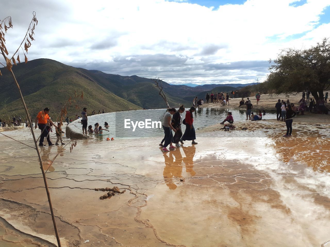 PEOPLE ON RIVERBANK AGAINST SKY