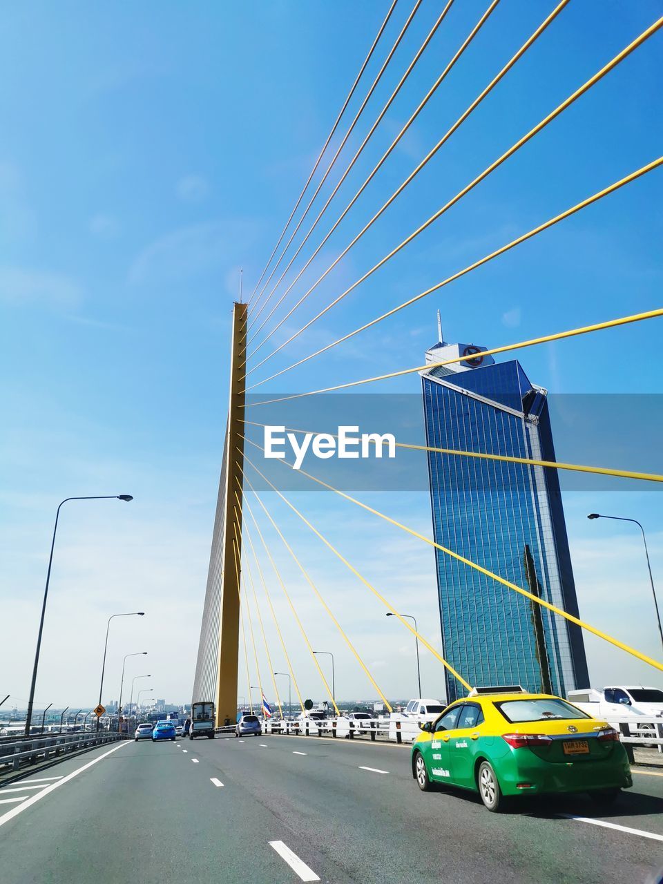 VEHICLES ON SUSPENSION BRIDGE AGAINST SKY