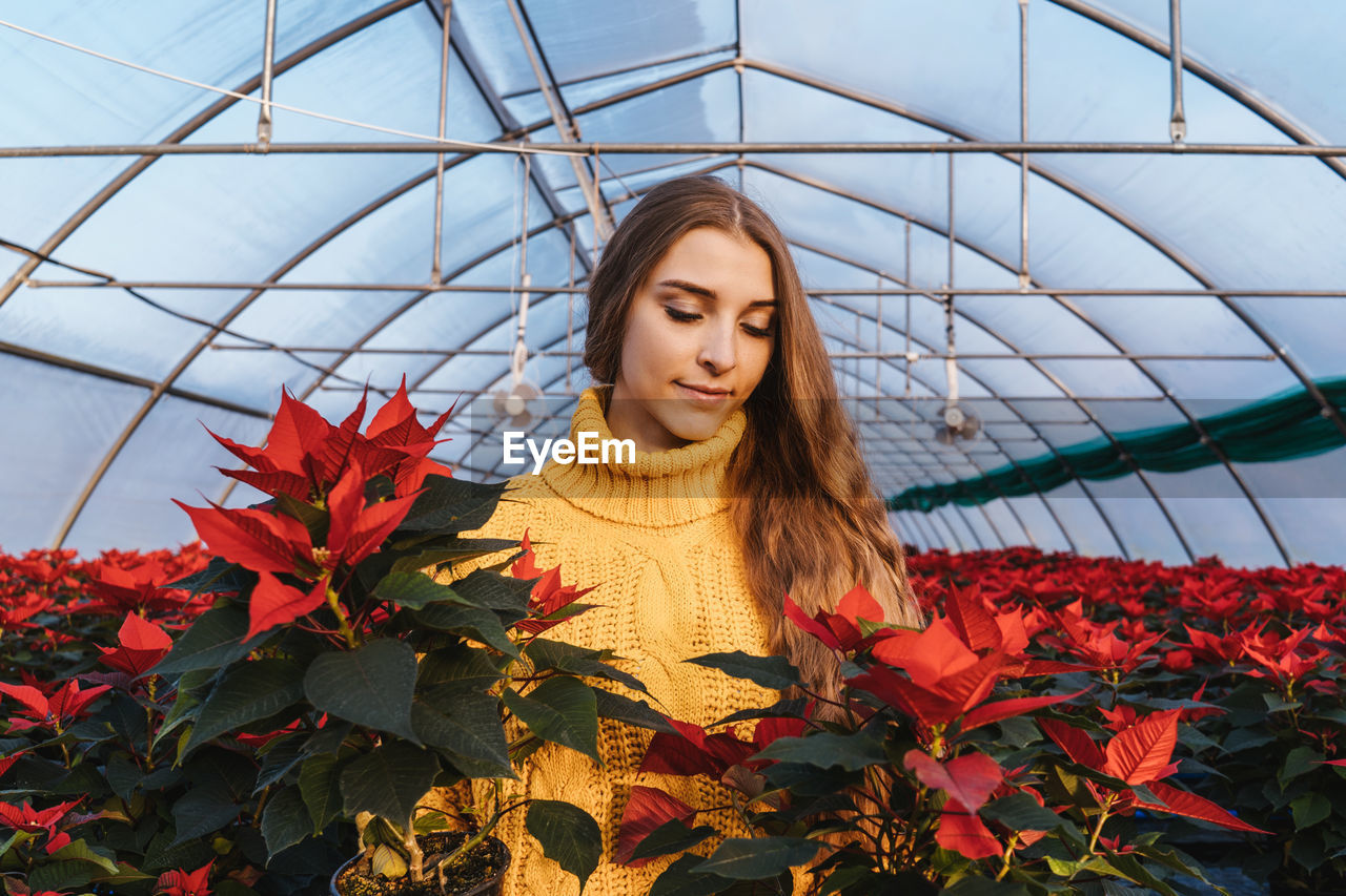 Young woman standing amidst plants in greenhouse